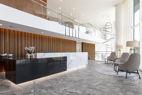 the lobby or reception area of a hotel with a reception desk and chairs