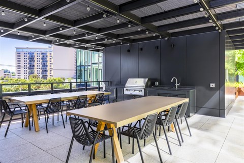 a communal area with tables and chairs and a kitchen