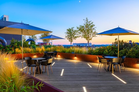 a patio with tables and umbrellas overlooking the ocean