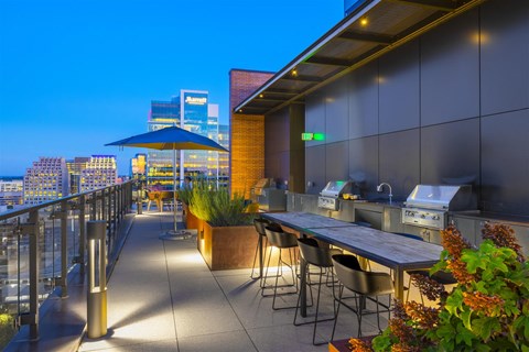 a rooftop bar with tables and chairs and a city skyline at night