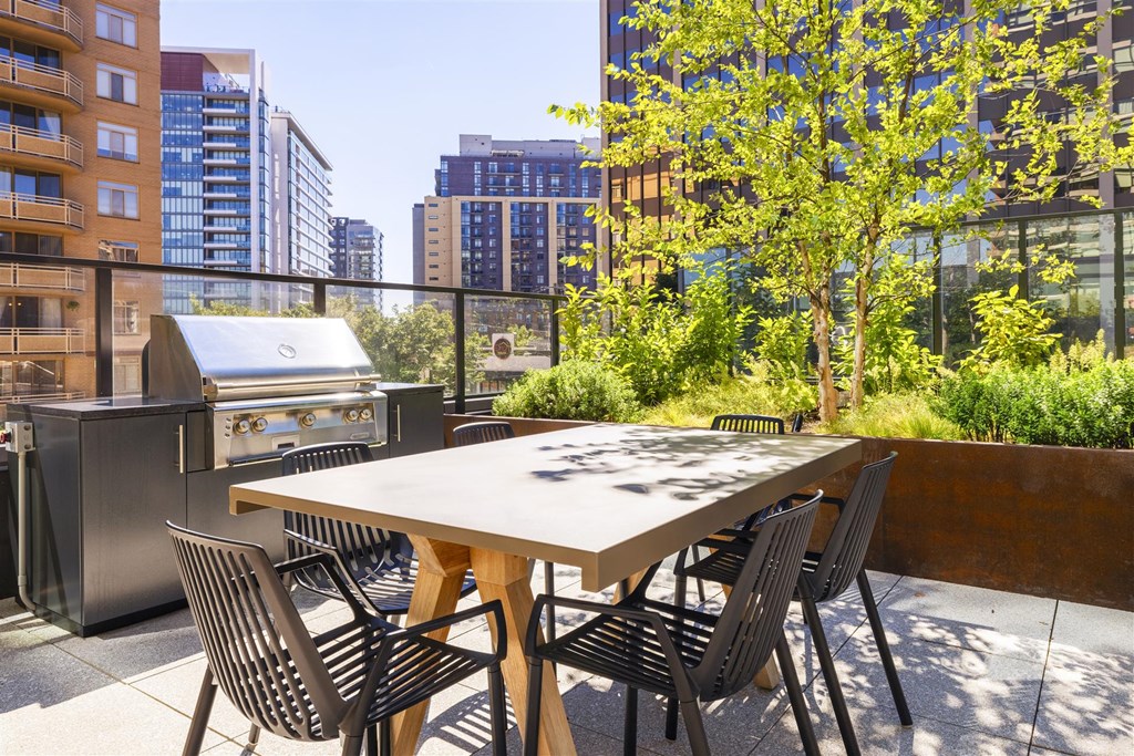 a patio with a table and chairs and a barbecue grill