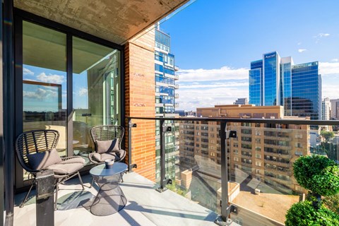 a balcony with two chairs and a table and a city in the background