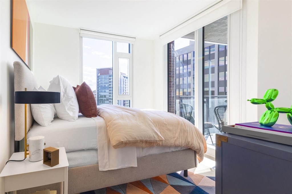 a bedroom with a bed and a large window and a city view