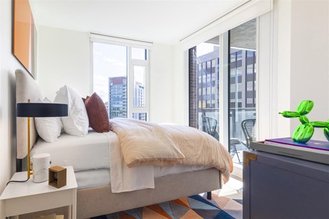 a bedroom with a bed and a large window and a city view