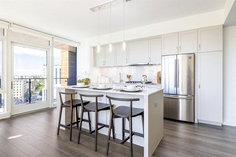 A kitchen with white cabinets and a stainless steel refrigerator.