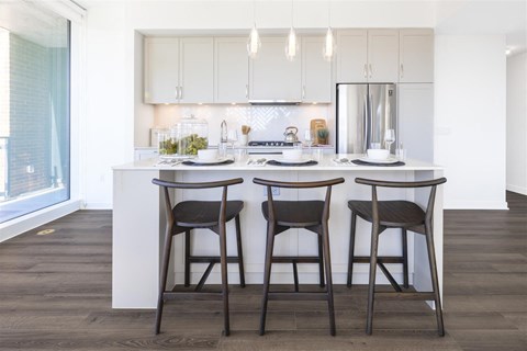 a kitchen with white cabinets and a counter top with three stools