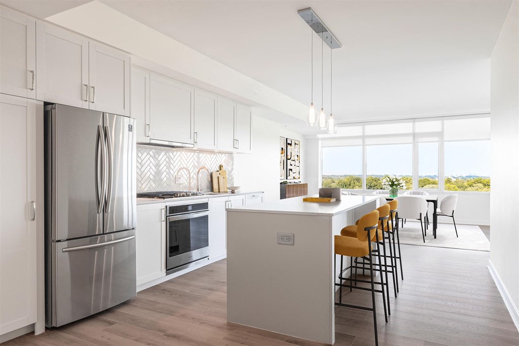 a white kitchen with a large island and stainless steel appliances