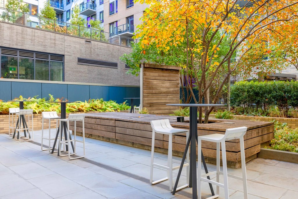 an outdoor patio with tables and chairs and a tree