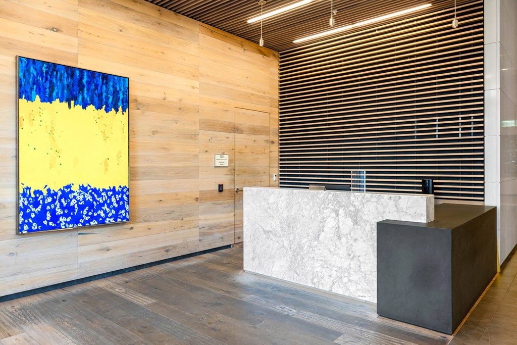 a reception desk in a lobby with a painting on the wall