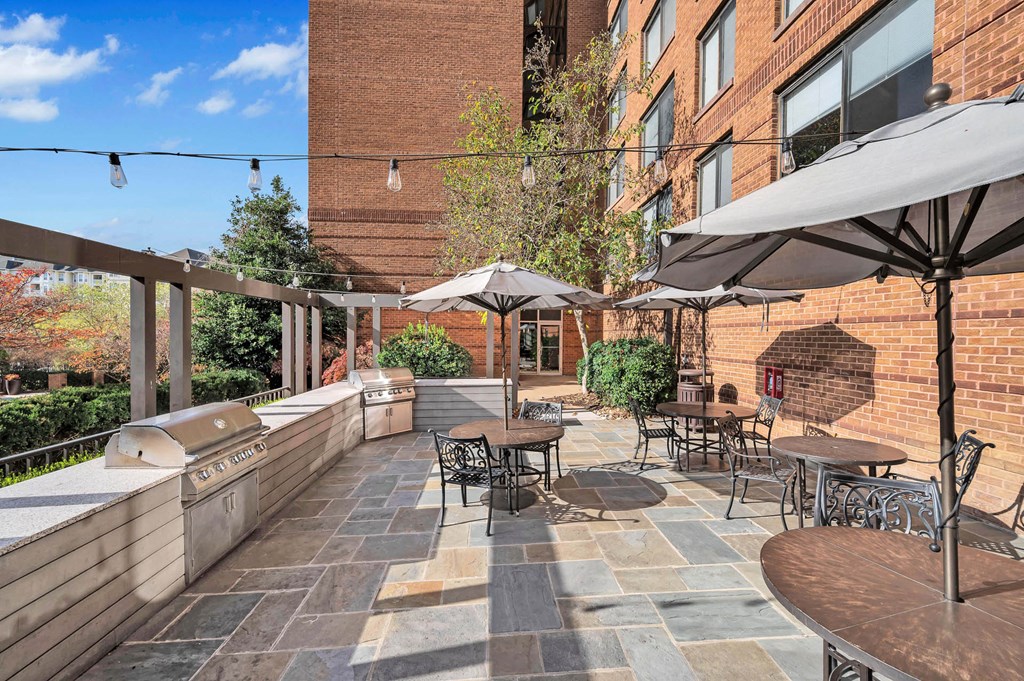 a patio with tables and umbrellas and a grill