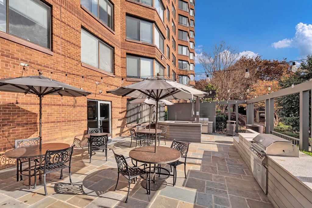 a patio with tables and umbrellas outside of a brick building