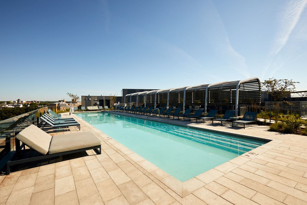 a pool on the rooftop of a hotel with lounge chairs