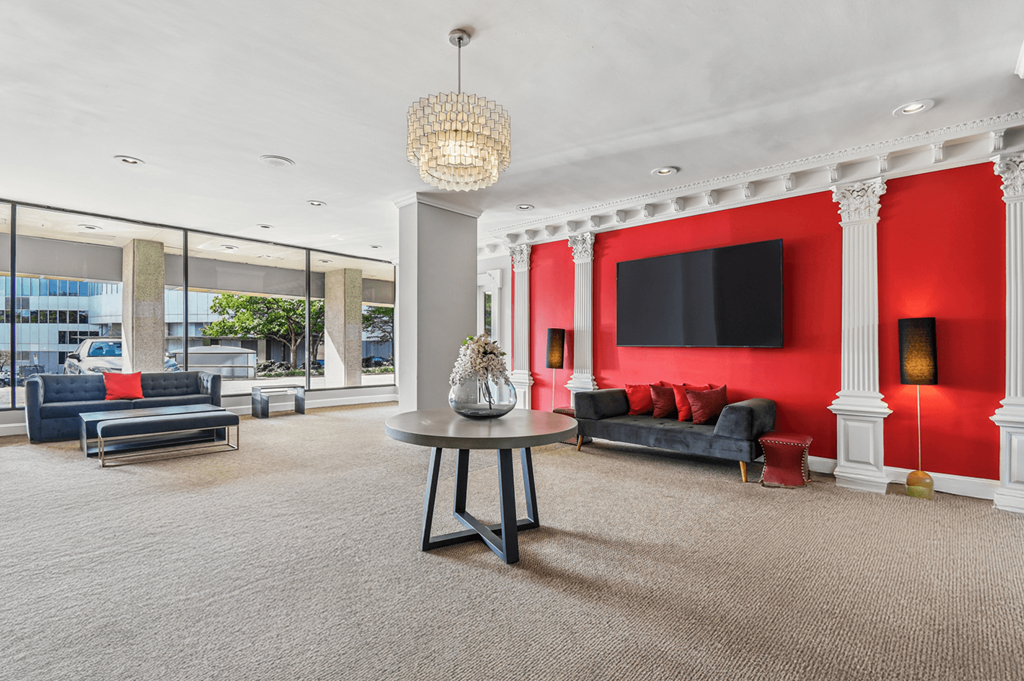 A living room with a grey carpet and a grey table with a vase on it.