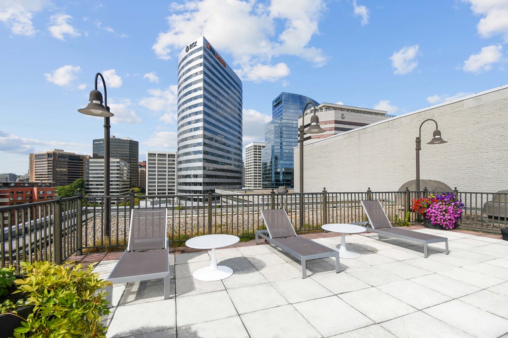 A rooftop patio with a table and chairs overlooking a city skyline.