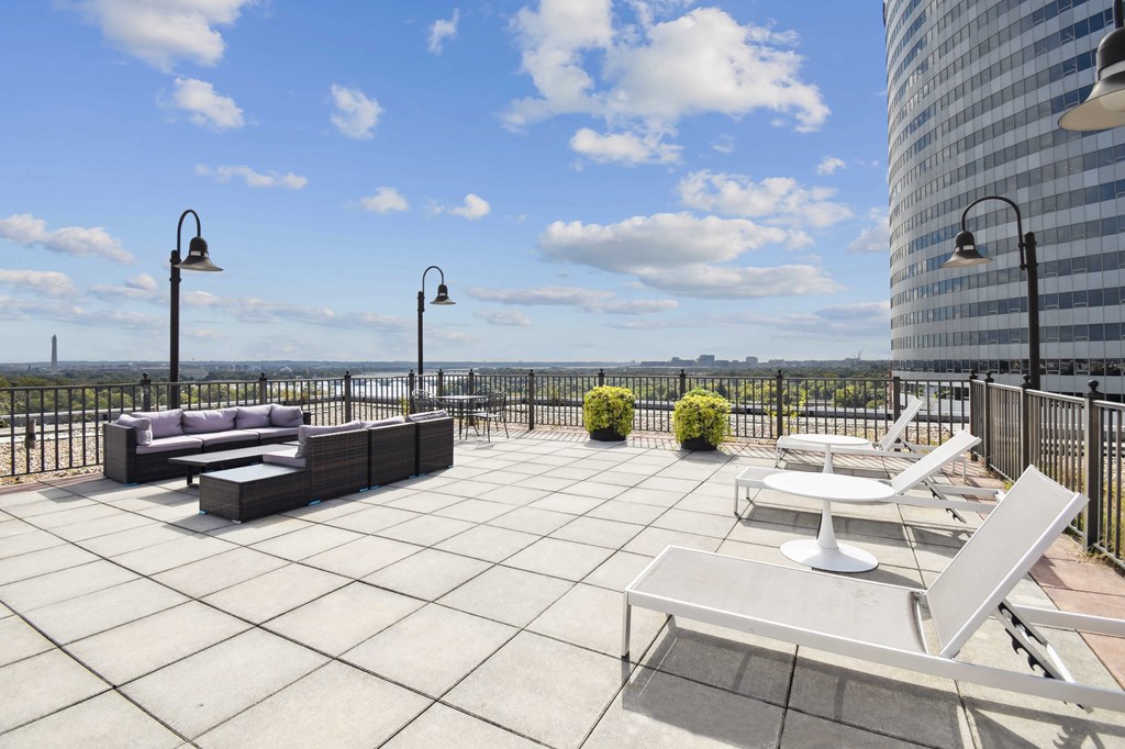 A patio with a couch, chairs, and a table with a view of the water.