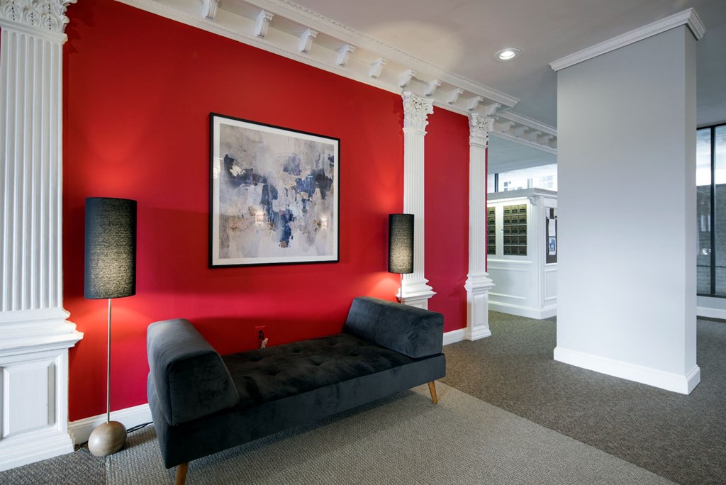 a living room with a red wall and a black couch