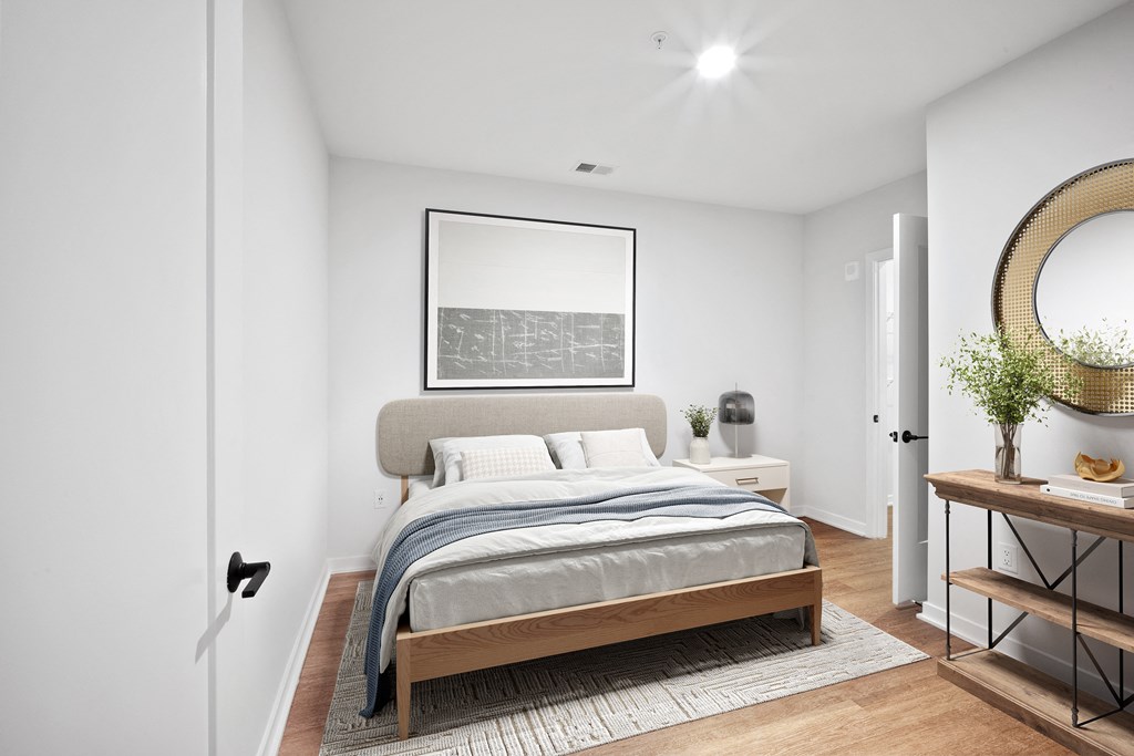 a bedroom with white walls and a bed with a gray blanket