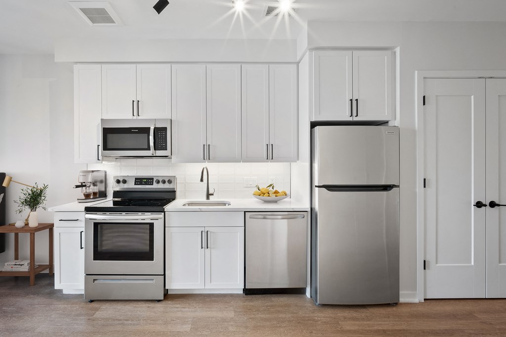 a white kitchen with stainless steel appliances and white cabinets