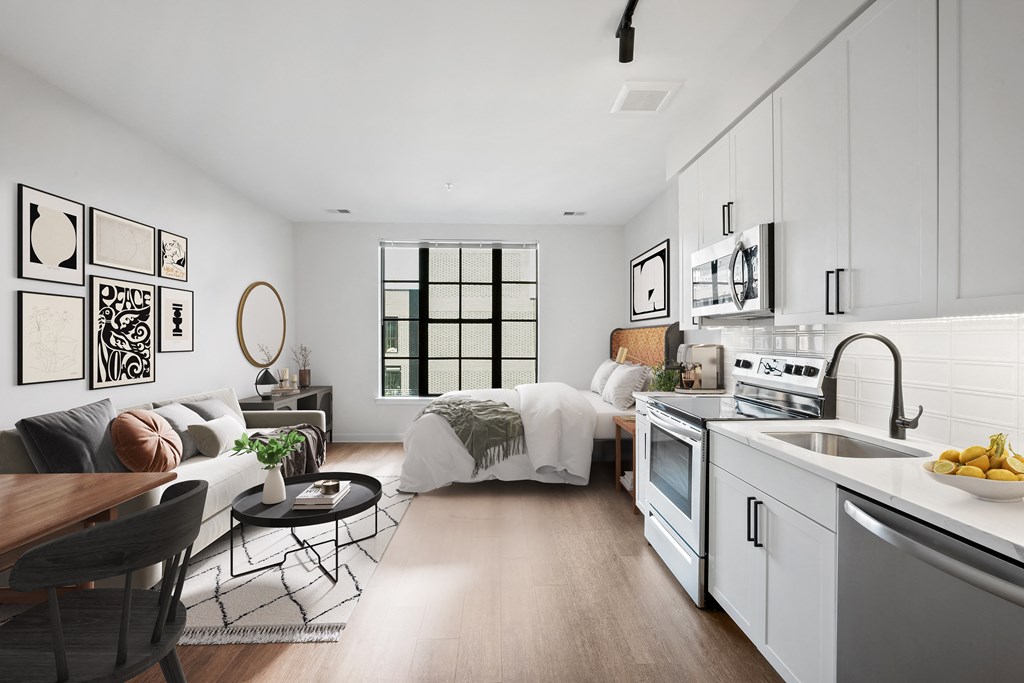 a white living room with a kitchen and a bed