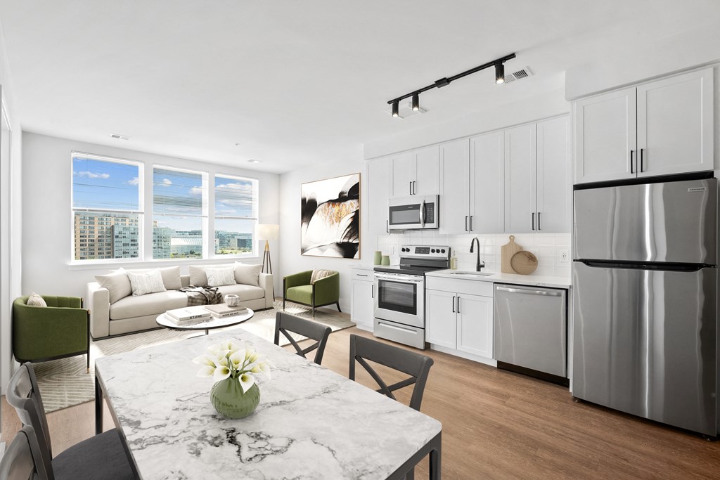 a kitchen and living room with white cabinets and stainless steel appliances