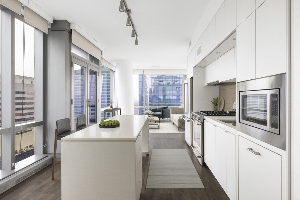a kitchen with white cabinets and a white counter top and a living room