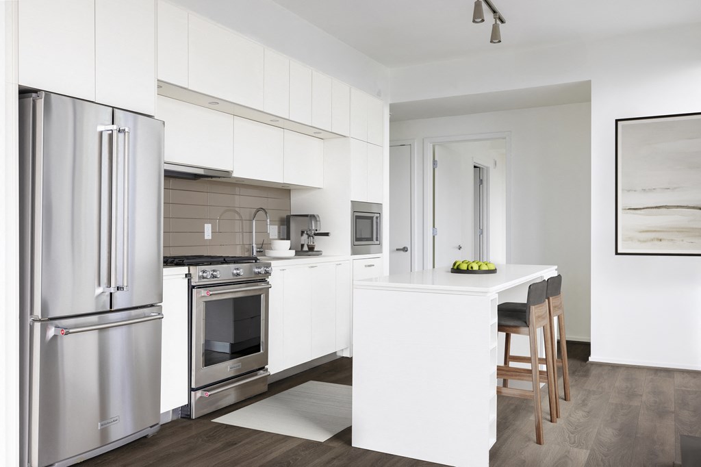 a white kitchen with a white island and stainless steel appliances