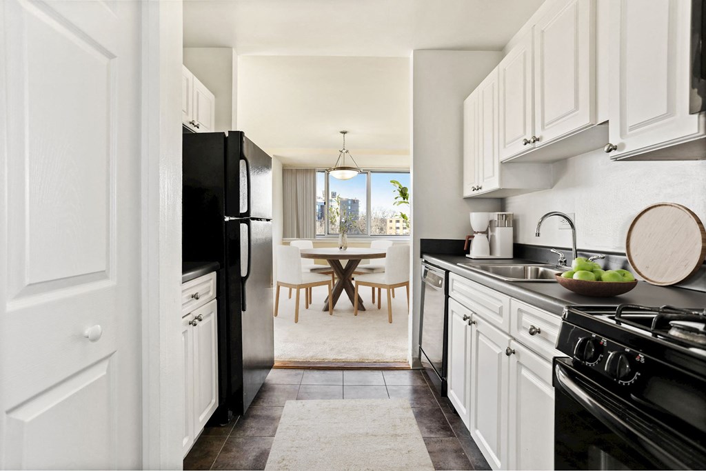 a kitchen with black appliances and white cabinets and a dining room with a table