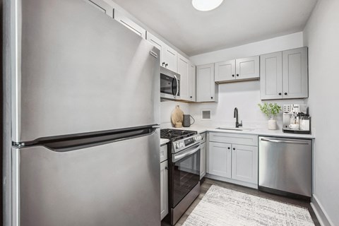 a white kitchen with stainless steel appliances and white cabinets