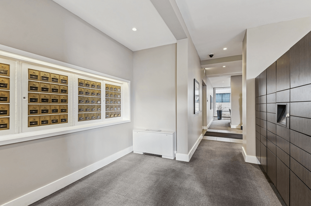 A hallway with a carpeted floor and a wall of lockers on the right.