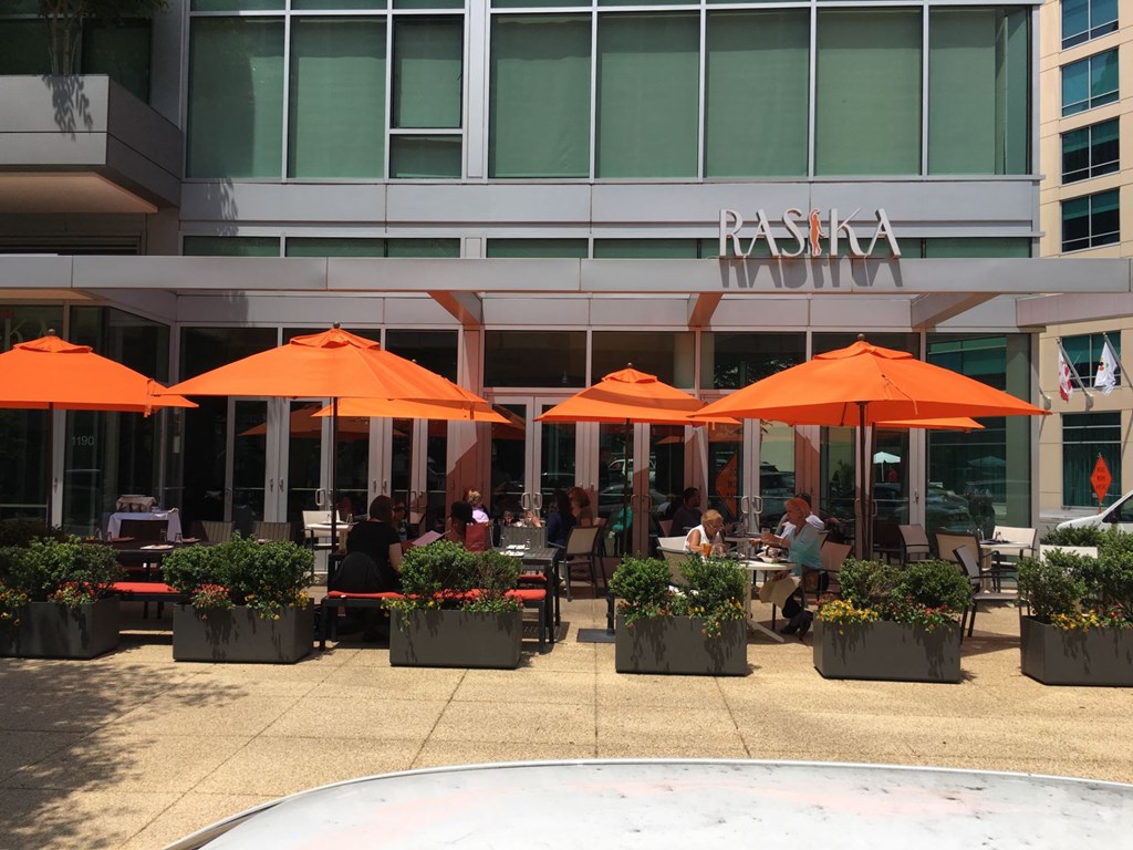 an outdoor restaurant with orange umbrellas in front of a building