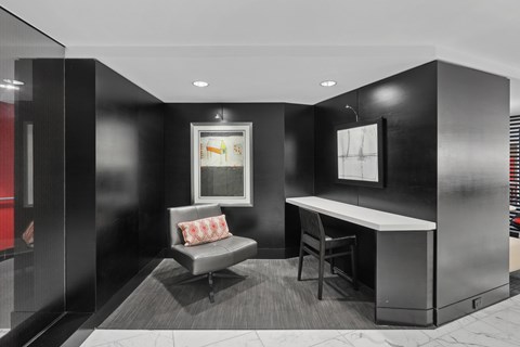 A black and white photo of a room with a couch, chair, and desk.