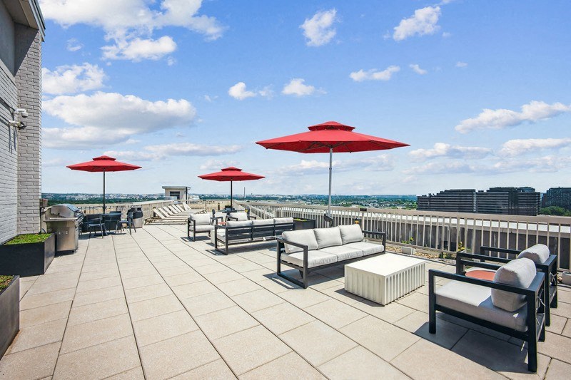 the rooftop terrace of a building with couches and umbrellas