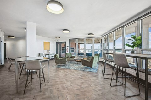 a living room with tables and chairs and a dining room with windows