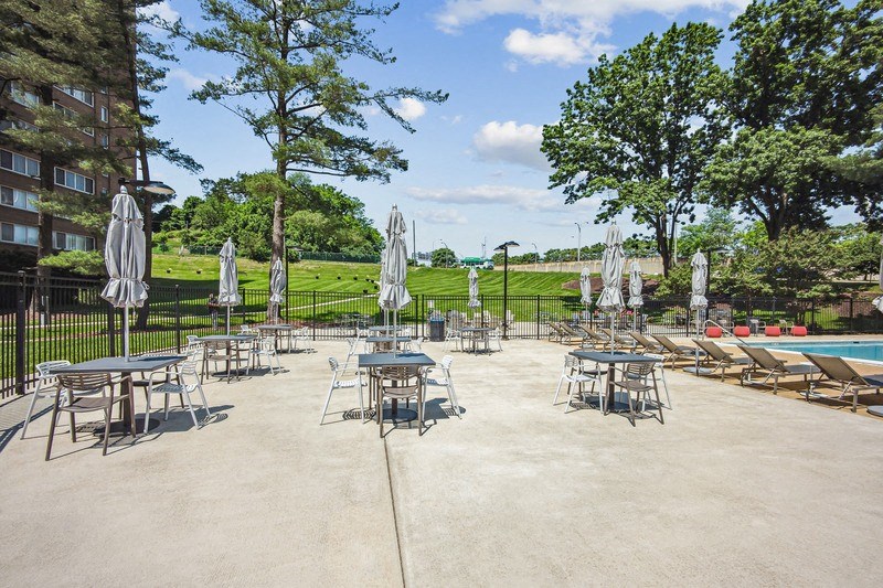 a patio with tables and umbrellas next to a pool