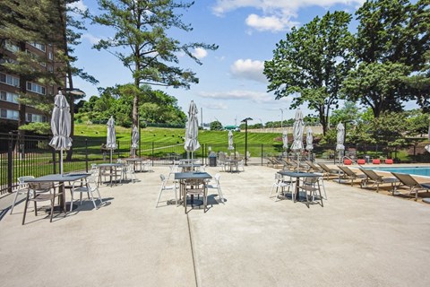 a patio with tables and umbrellas next to a pool