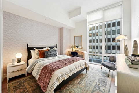 A bedroom with a large bed and a window overlooking a building.