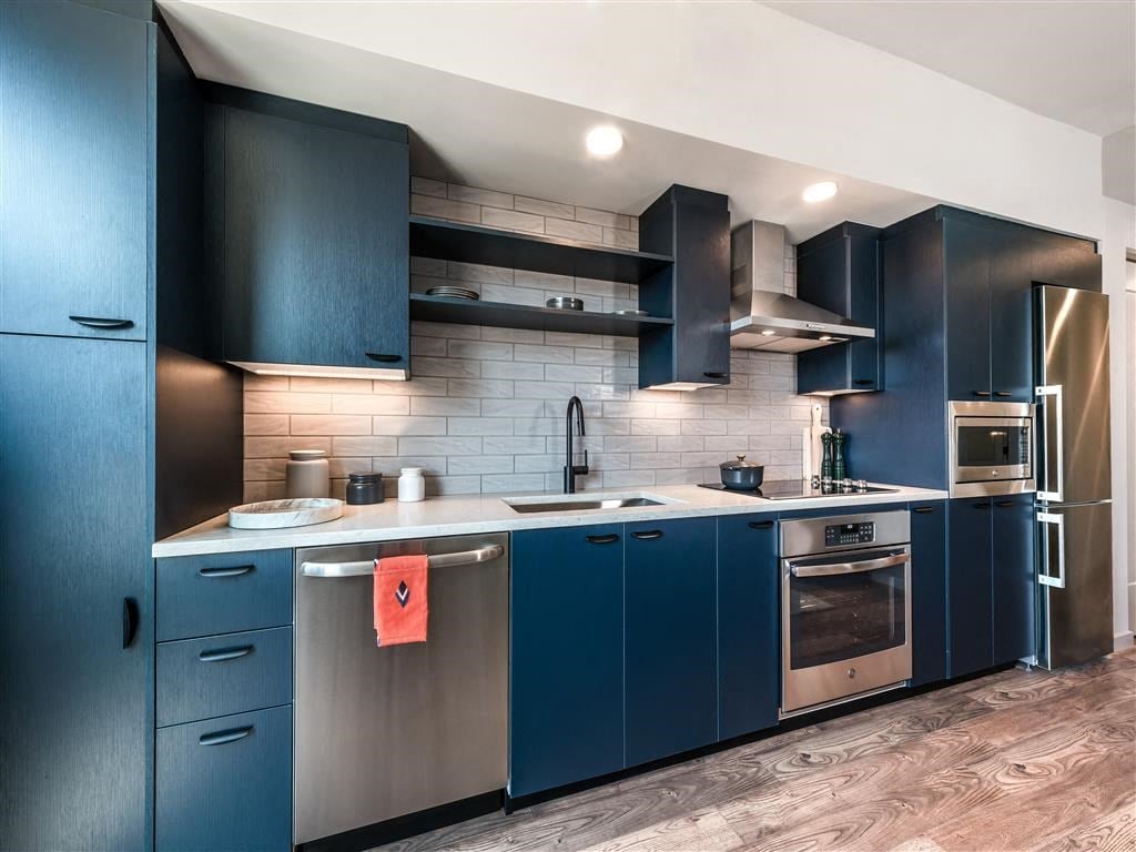 a blue kitchen with stainless steel appliances and blue cabinets