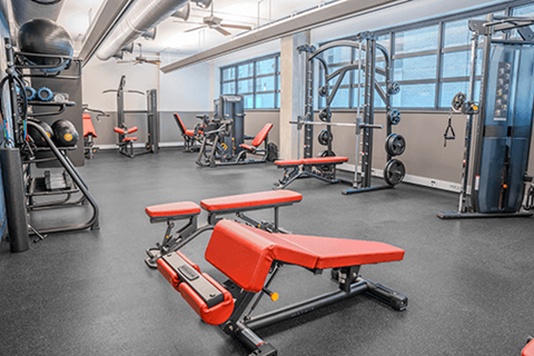 A gym with a variety of equipment including weights and benches.