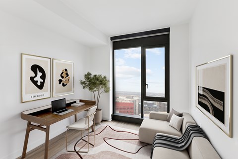 A modern living room with a laptop on the desk and a view of the city through the window.