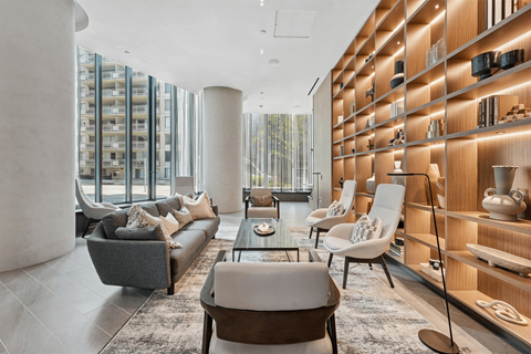 A modern living room with a large grey sofa and a wooden shelf with various objects on it.
