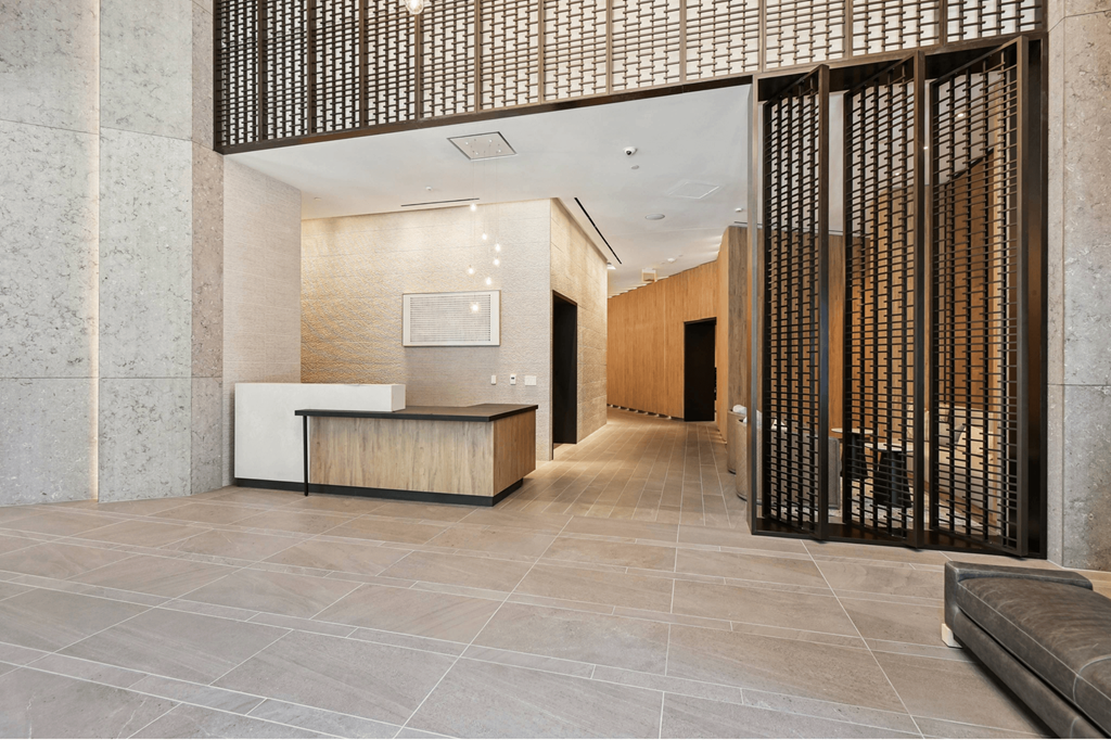 A modern office lobby with a reception desk and a large screen on the wall.