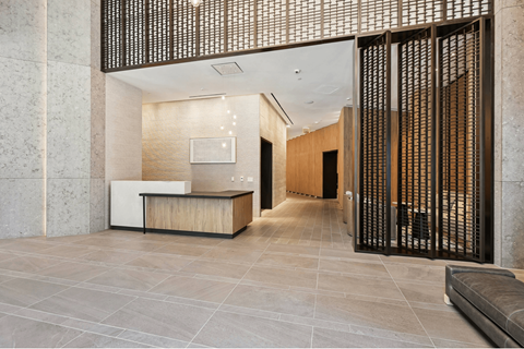 A modern office lobby with a reception desk and a large screen on the wall.