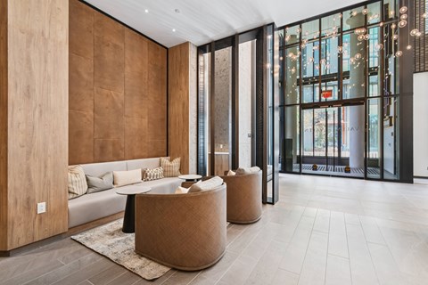 A modern living room with a white couch and a brown woven ottoman.