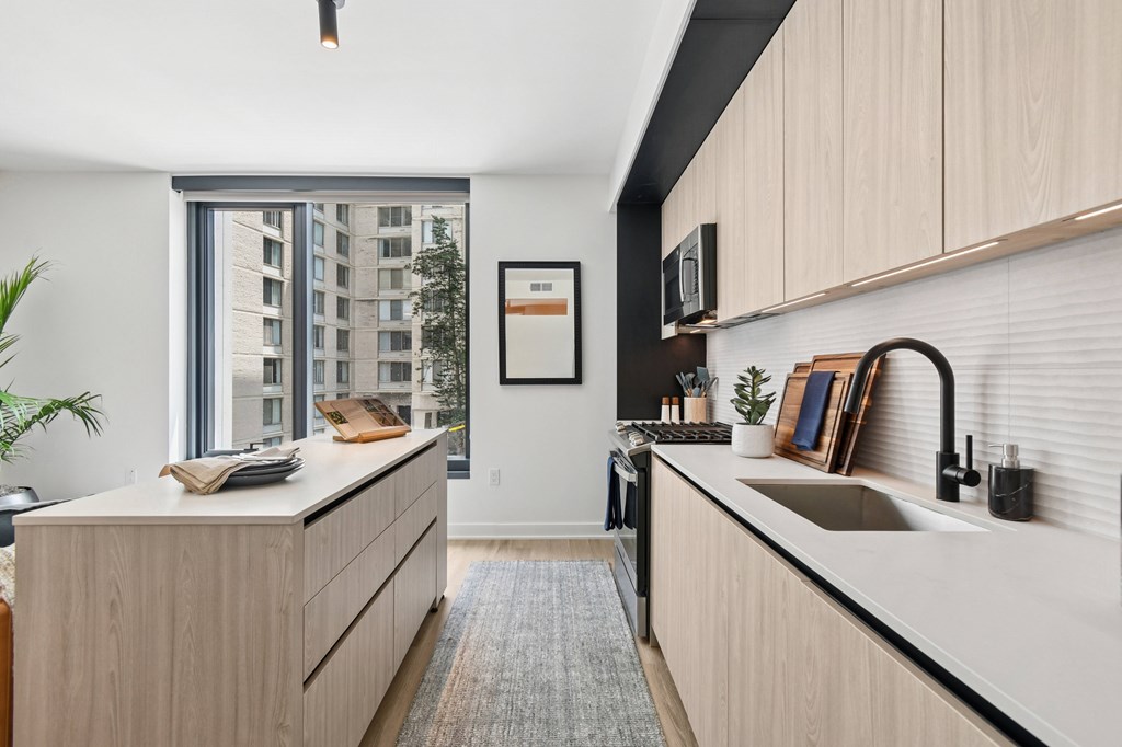A modern kitchen with wooden cabinets and a large window.