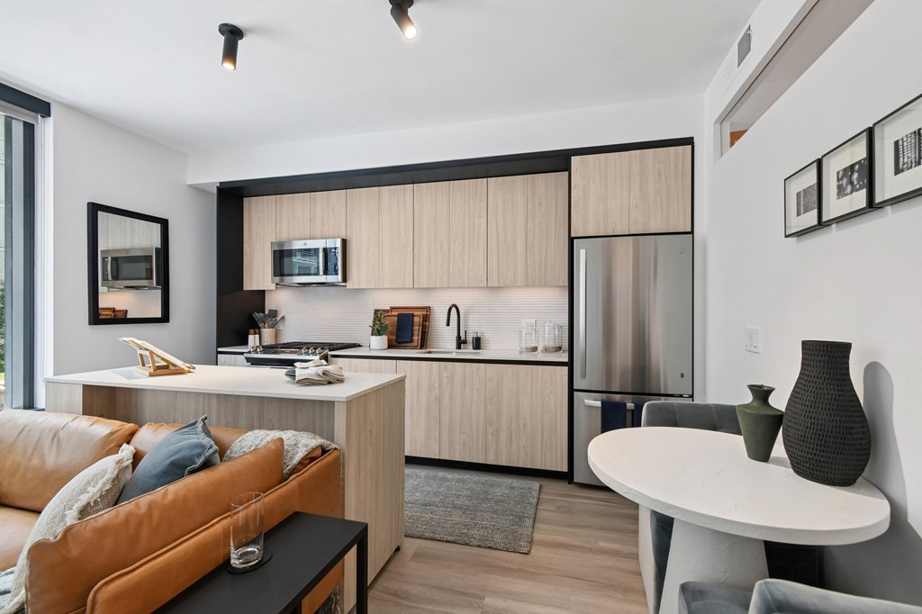 A modern kitchen with a refrigerator, microwave, and oven.
