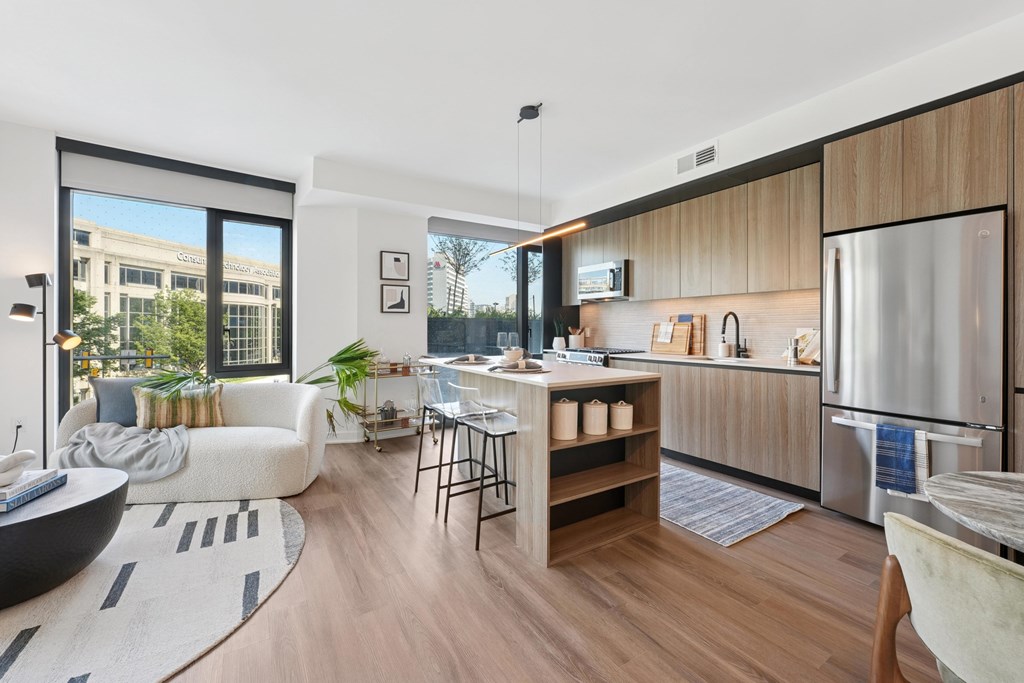 A modern kitchen with a refrigerator, sink, and a dining table with chairs.