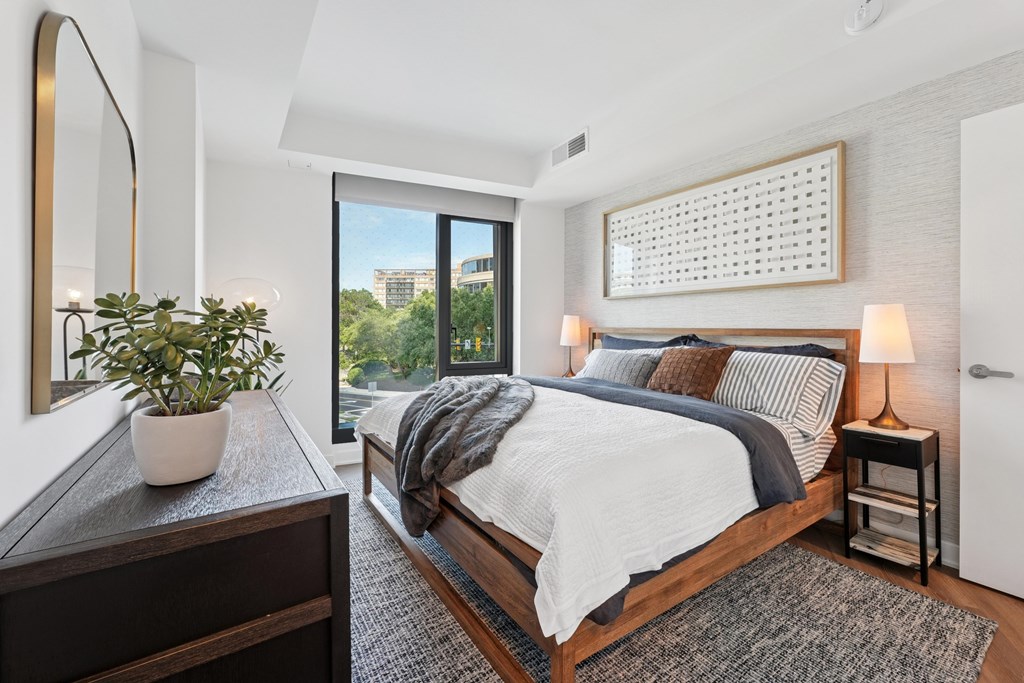 A bedroom with a large bed, a potted plant, and a mirror on the wall.