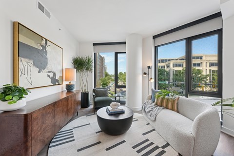 A modern living room with a large window and a view of a building outside.