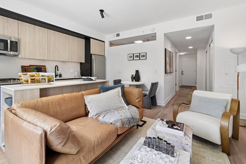 A modern living room with a brown leather couch and a coffee table with glasses on it.