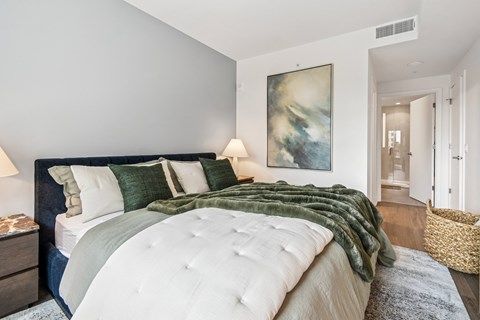 A bedroom with a large bed and a painting on the wall.